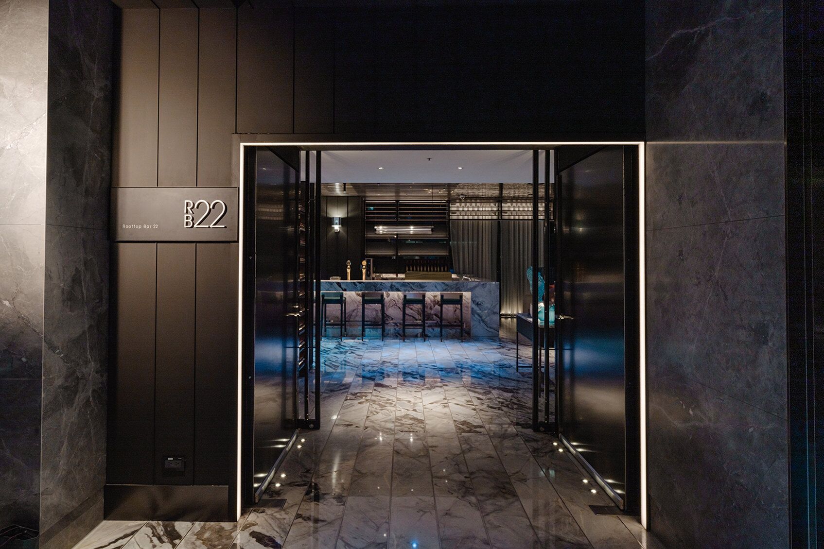 A modern bar area with a marble floor, bar stools, and a counter.