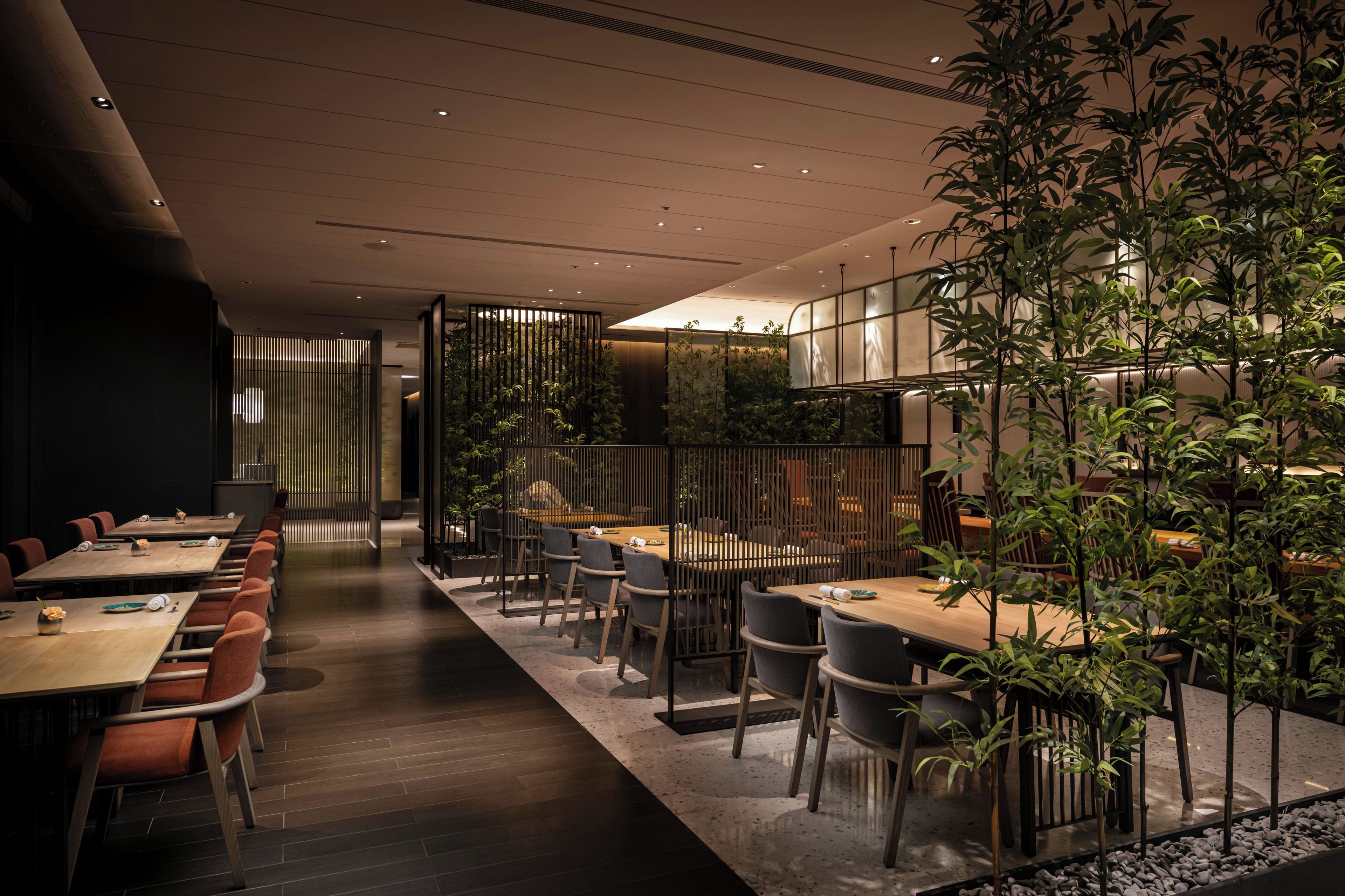 A modern dining area with long tables, chairs, and vertical gardens.