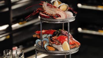 A seafood platter on a three-tiered stand with glasses and cutlery beside it.