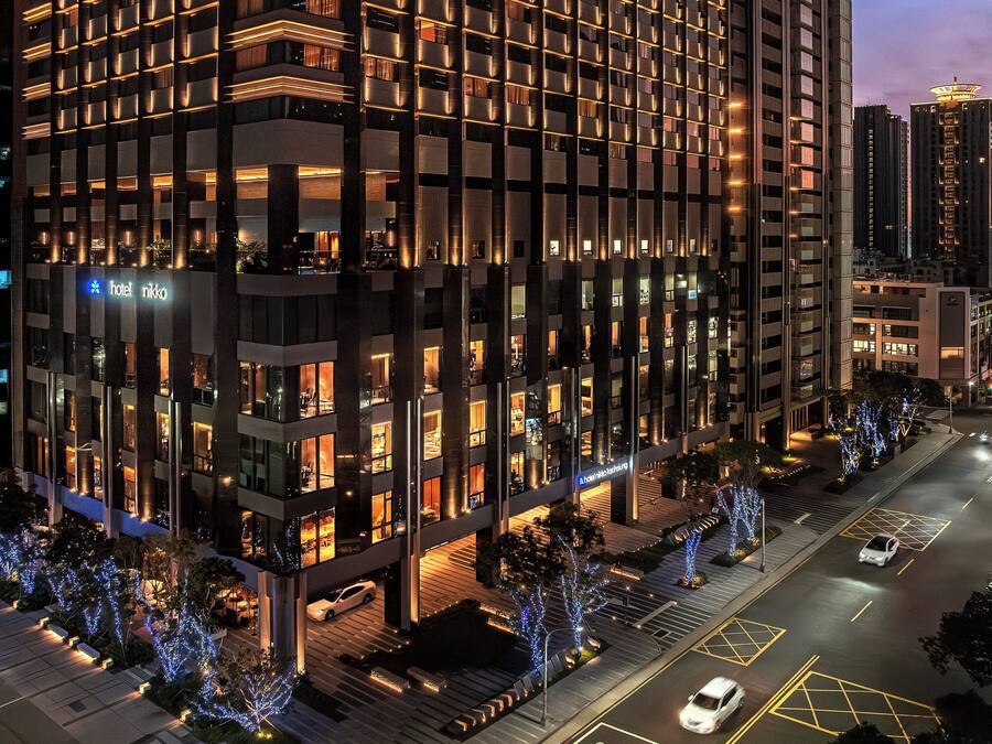 A modern hotel with multiple floors, illuminated windows, and a well-lit entrance area.