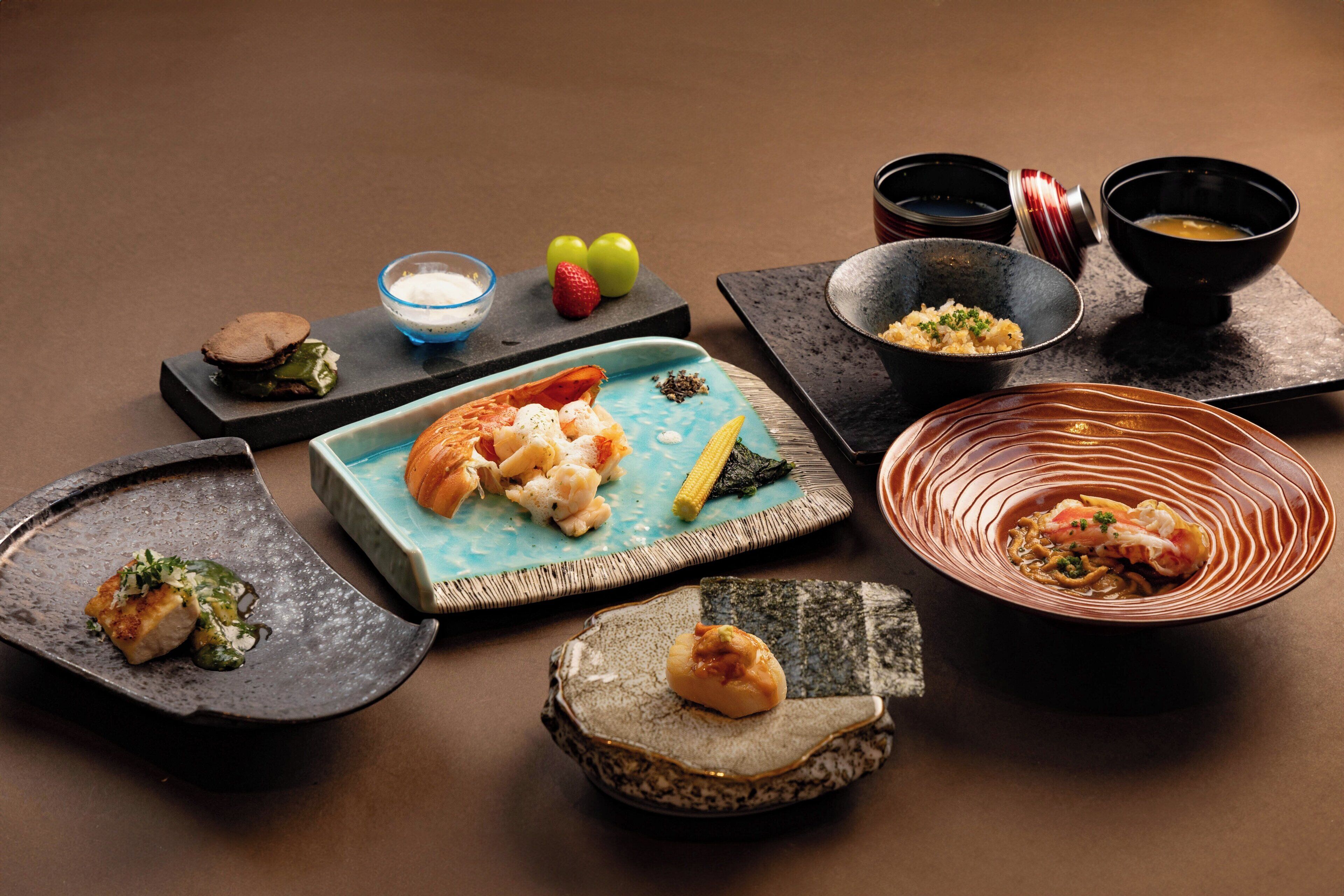 A variety of dishes on a table, including sushi, sashimi, and a bowl of soup.