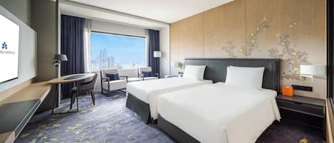 A hotel room with two beds, a desk, a chair, a TV, and a large window with a city view.