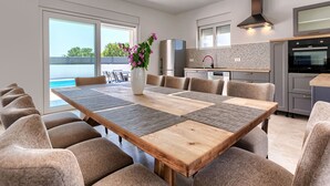 A modern kitchen with a large island, stainless steel appliances, and a view of the outdoors. - Vacation home Kliska by Interhome (Pula)