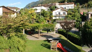 A residential area with houses, a playground with a slide, and a mountain in the background.