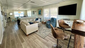 A spacious living area with a kitchen, a dining area, and a large TV.