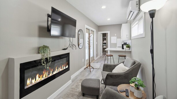 A modern living room with a fireplace, grey sofas, a TV, and a floor lamp.