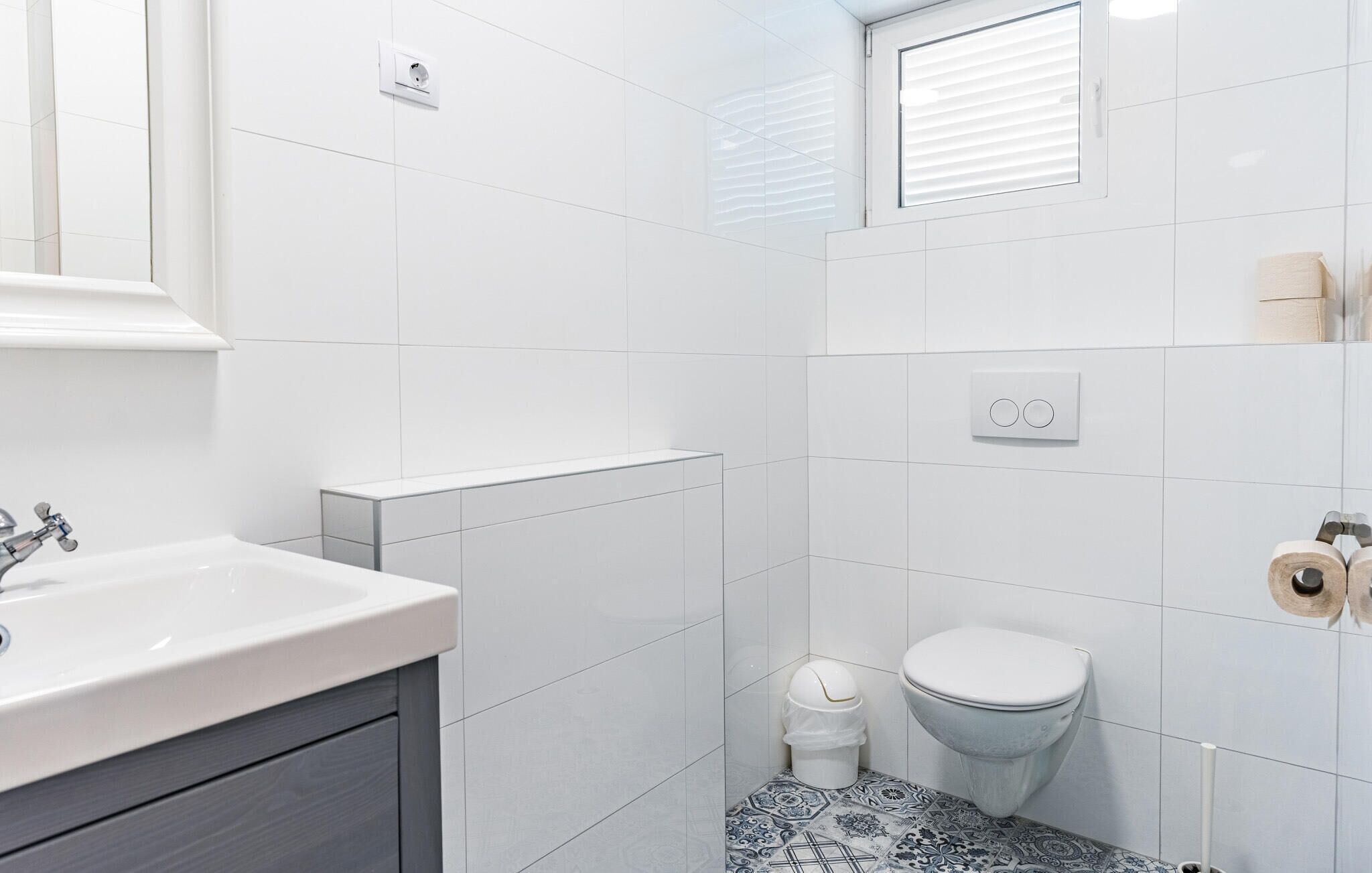 A modern bathroom with a white sink, a toilet, and a shower area.