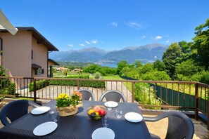 A balcony with a table set for two, overlooking a mountainous landscape.