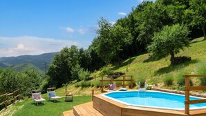 A wooden deck with a hot tub, surrounded by a grassy area and trees. - Olimpia by Interhome (Borgo San Lorenzo)