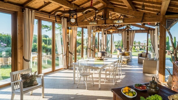 Une salle à manger spacieuse avec un plafond en bois, de grandes fenêtres et une vue sur le jardin.