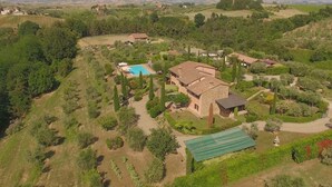 Vue aérienne d’une propriété située à la campagne, avec une grande maison, une piscine et des jardins environnants.