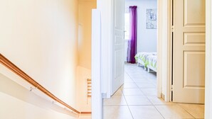 A staircase leading to a bedroom with a bed and a window with purple curtains. - Villa Les Genêts by Interhome (Montauroux)