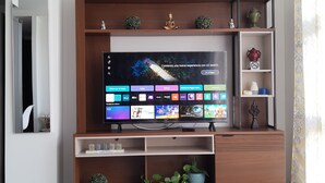 A modern entertainment unit with a flat-screen TV, shelves with decorative items, and a small potted plant.
