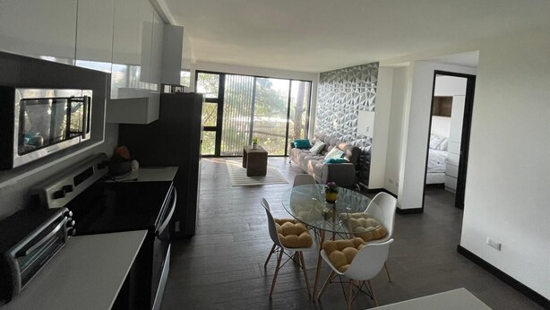 A modern kitchen with a built-in oven and a dining area with a glass table and chairs.