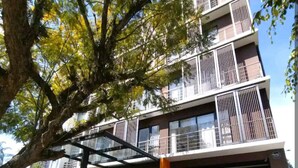 A modern multi-story building with balconies, a covered entrance, and a staircase leading to the main entrance.