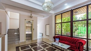 A hotel lobby with a red sofa, a chandelier, a large window, and a tiled floor.