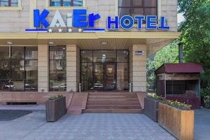 The exterior of the Kai Hotel with a clear entrance, steps leading up to the doors, and a sign above the entrance.