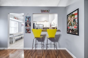 Una cocina moderna con armarios blancos, un refrigerador de acero inoxidable y un taburete amarillo.