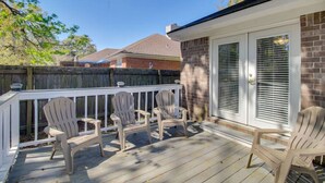 A covered deck with Adirondack chairs, a brick wall, and a sliding glass door. - Totally 80"s Hideaway (Savannah)