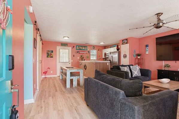 Un espacio habitable compacto con kitchenette, comedor y sala de estar con sofá y mesa de centro.