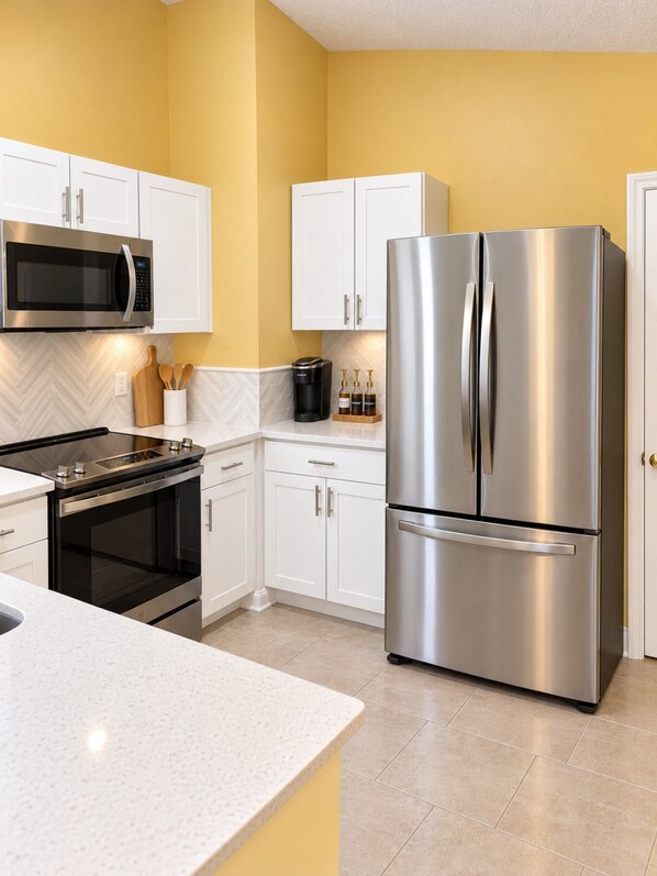 A modern kitchen with white cabinets, stainless steel appliances, and a herringbone-patterned backsplash.