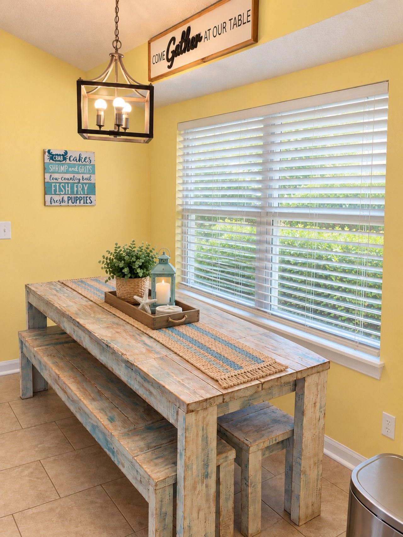 A dining area with a wooden bench and table, a hanging light fixture, and a window with blinds.