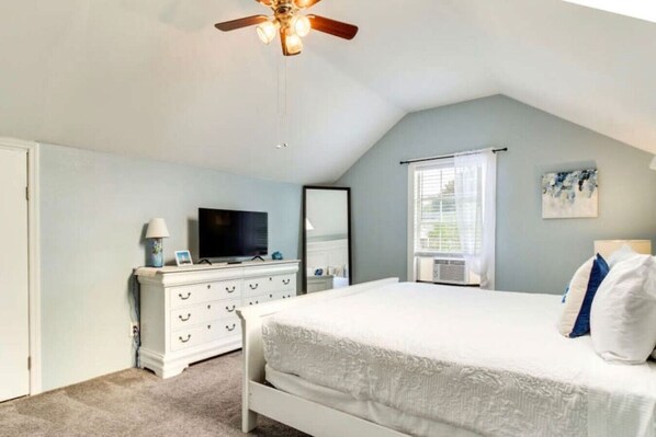 A bedroom with a bed, a dresser, a television, and a ceiling fan. - The Turtle Pond Oasis (Savannah)