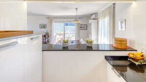 A modern kitchen with a central island, white cabinetry, and a view to an outdoor balcony.