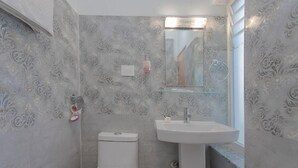 A bathroom with a toilet, a sink, and a mirror. - Hotel Tiktok (Kathmandu)