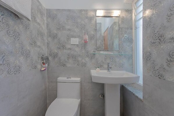 Une salle de bain avec des toilettes, un lavabo et un miroir.