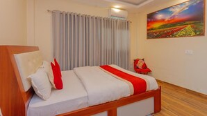 A hotel room with a bed, curtains, an air conditioning unit, and a painting on the wall. - Hotel Tiktok (Kathmandu)