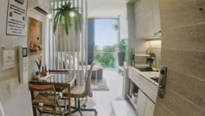 A compact kitchen with a dining area, a small sink, and a potted plant. - Rocco 513 - Corner 1 Bedroom Serviced Apartment With Seaview (Krabi)