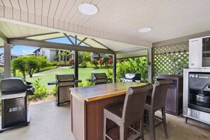 Une terrasse extérieure avec un espace bar, un barbecue et des sièges.