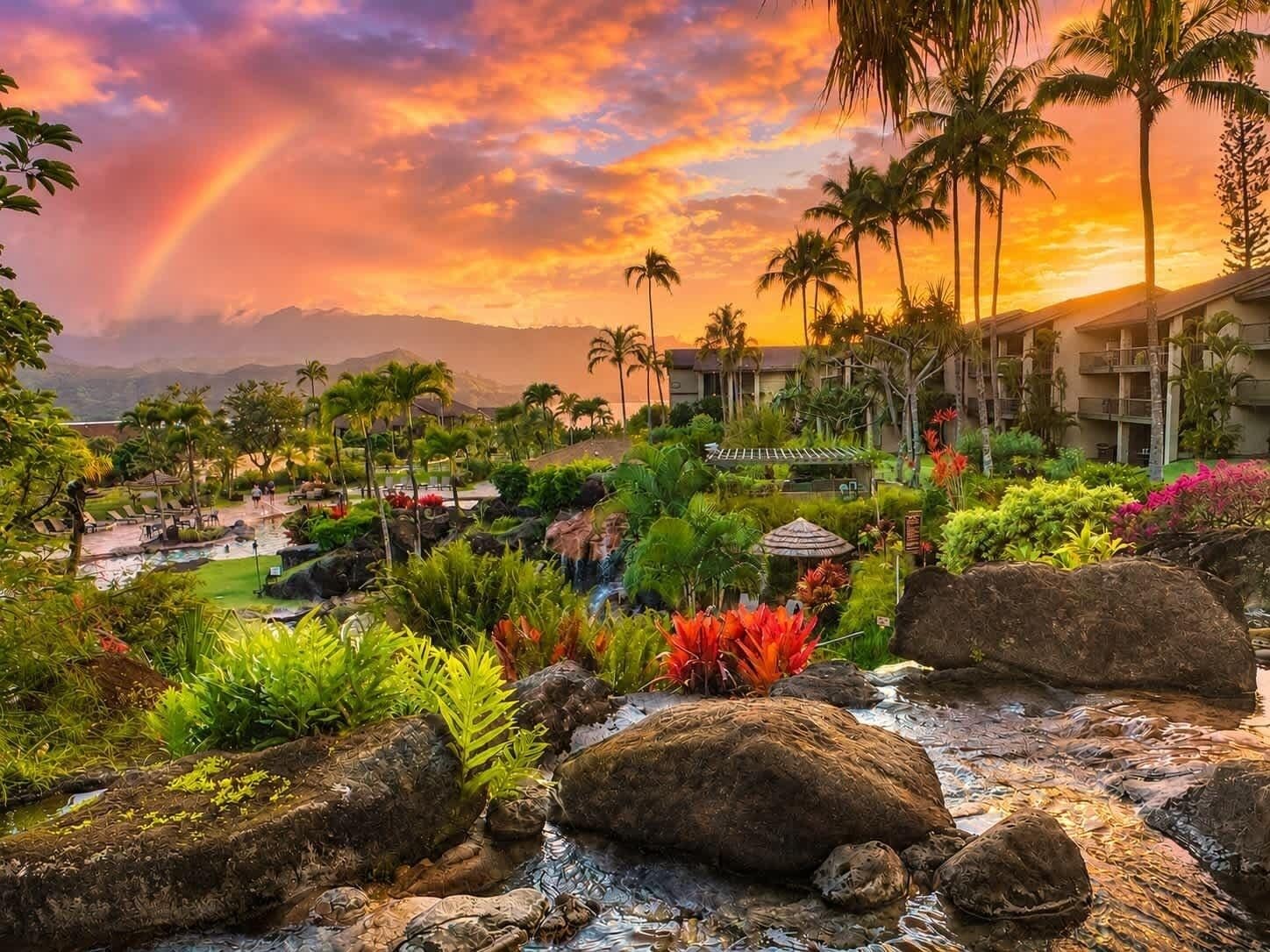 A resort with a pool, palm trees, and a waterfall.