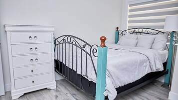 A bedroom with a bed, a white dresser, and a nightstand.