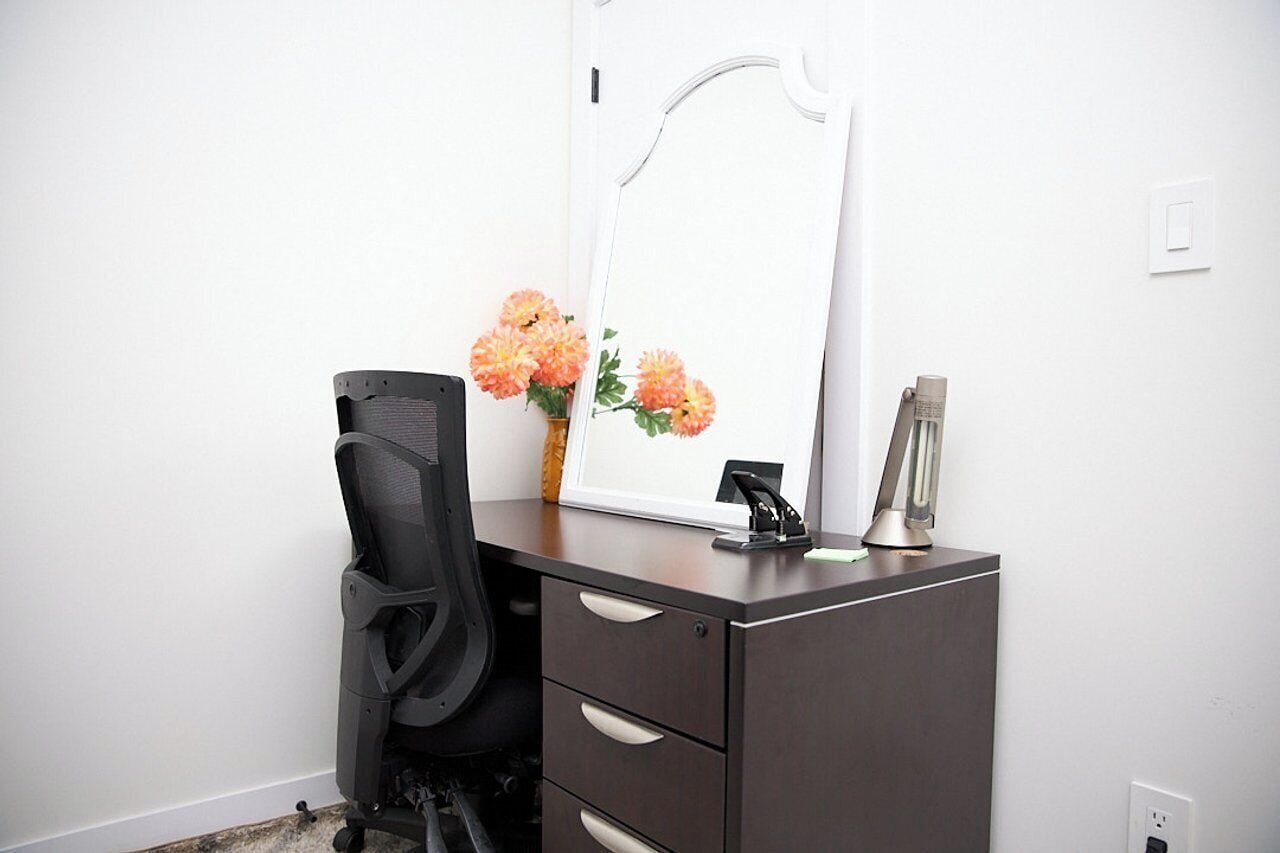 A small office space with a desk, chair, and a mirror.