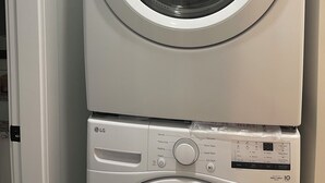 A stacked washer and dryer unit with control panels and a digital display. - Cozy 3-bedroom, 3 queen beds ground level suite in a desirable location in PG.  (Prince George)