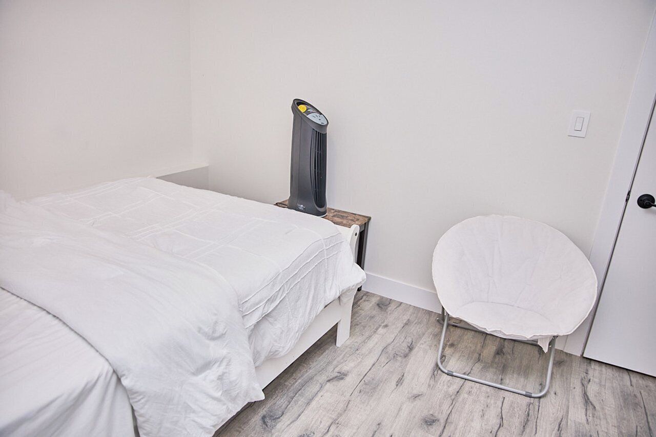 A bedroom with a bed, a chair, a heater, and a door.