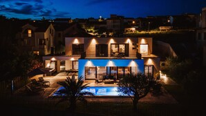 A modern two-story house with a swimming pool, outdoor seating, and a well-lit balcony. - Lovely home in Razanac (Razanac)