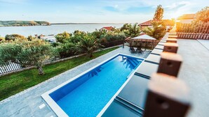 Una piscina rettangolare con una superficie d'acqua cristallina, circondata da un solarium in pietra.