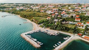Vista aerea di una cittadina costiera con un porto turistico, case e una chiesa.
