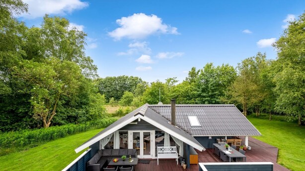 Una casa moderna con una amplia terraza, un comedor y una zona de estar acogedora.