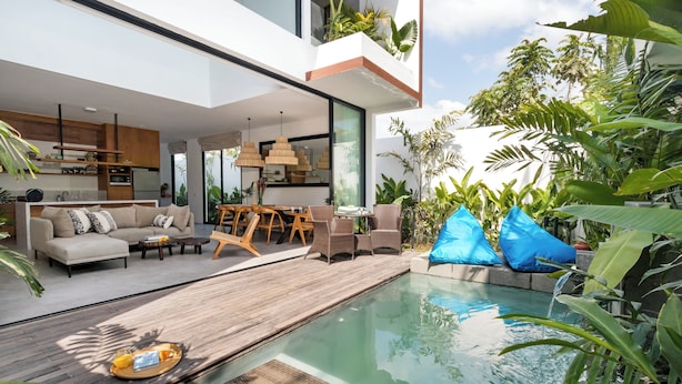 Una zona living esterna moderna con piscina, terrazza in legno e mobili da giardino.