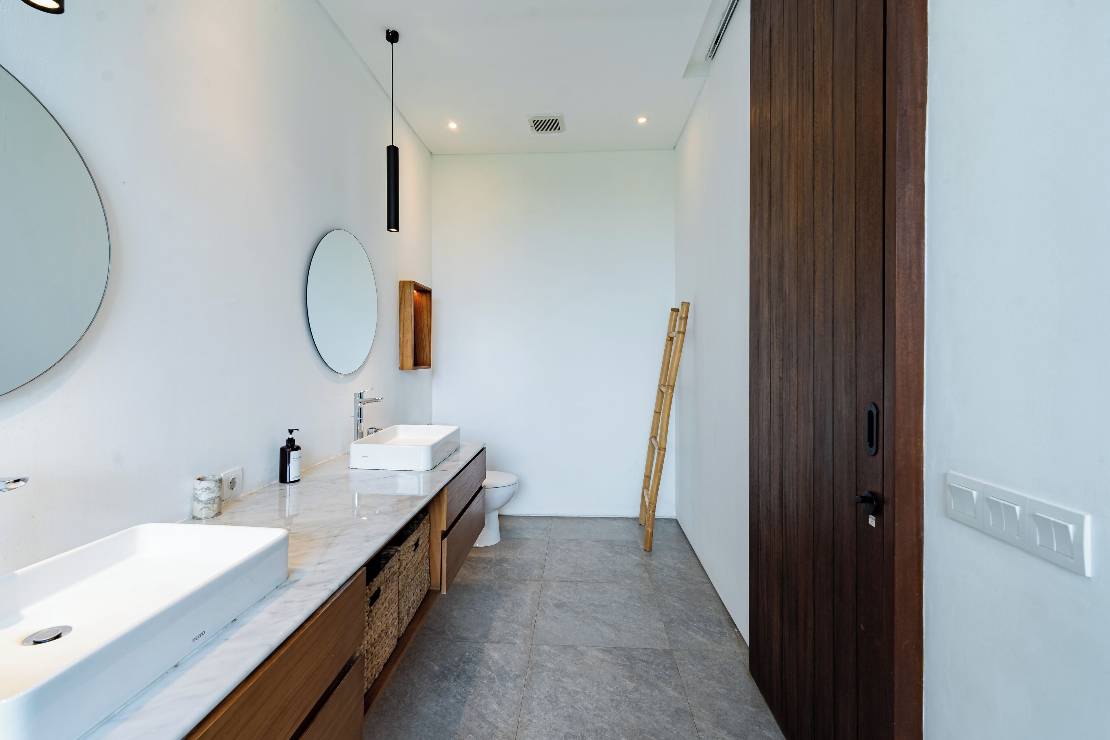 Un baño moderno con un espejo grande, un lavabo blanco y un inodoro.