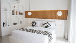 A modern hotel room with a large bed, white walls, and a wooden panel accent. - Playa Canggu 7 (Canggu)