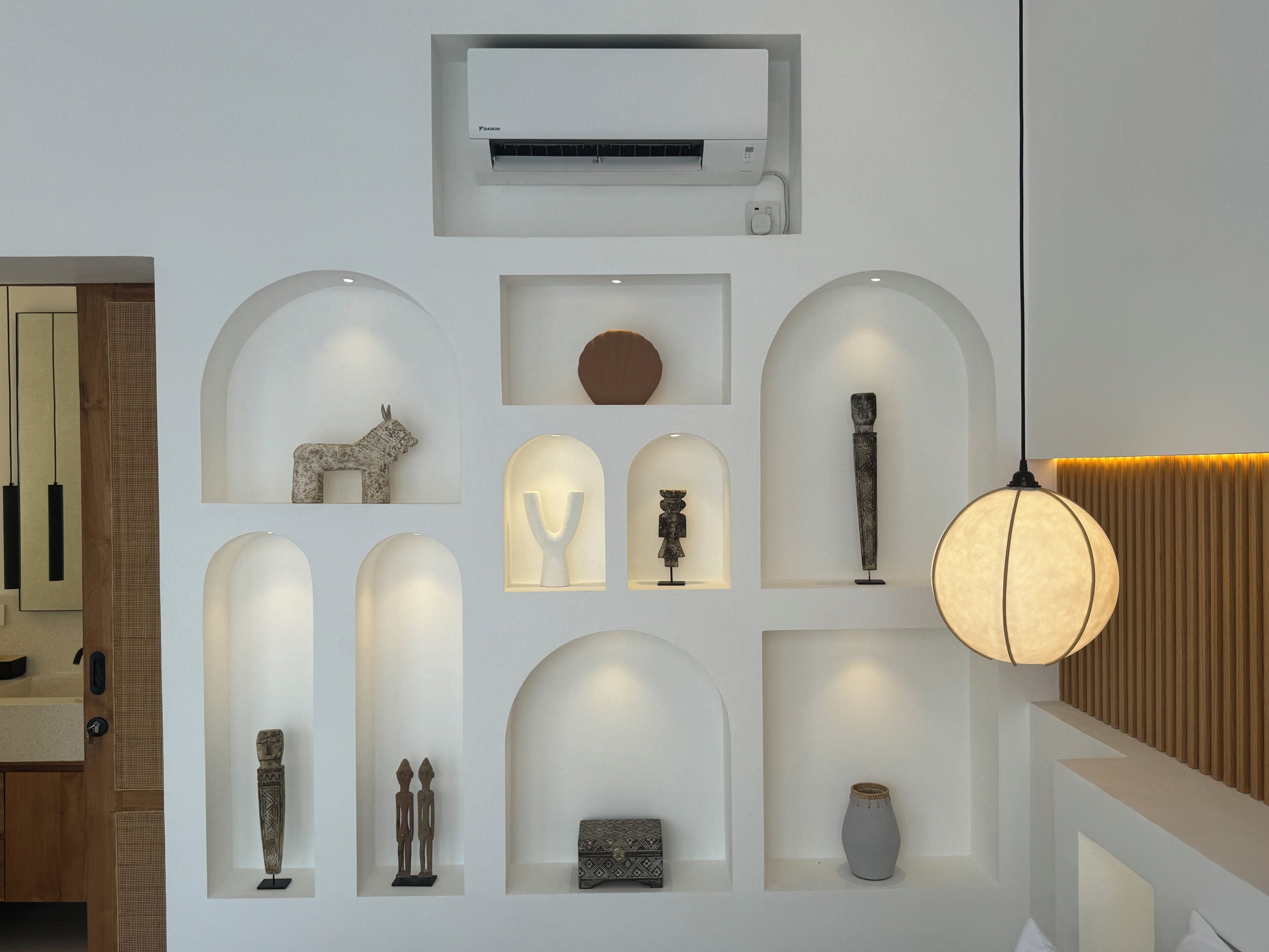 A modern interior with a central air conditioning unit, multiple display cases with artifacts, and a hanging light fixture.