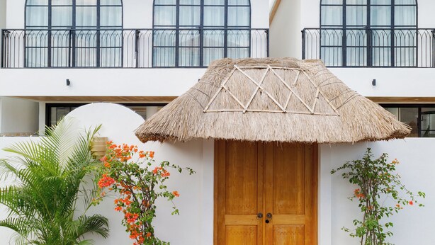 A modern building with a large wooden door, arched windows, and a thatched roof entrance. - Playa Canggu 7 (Canggu)