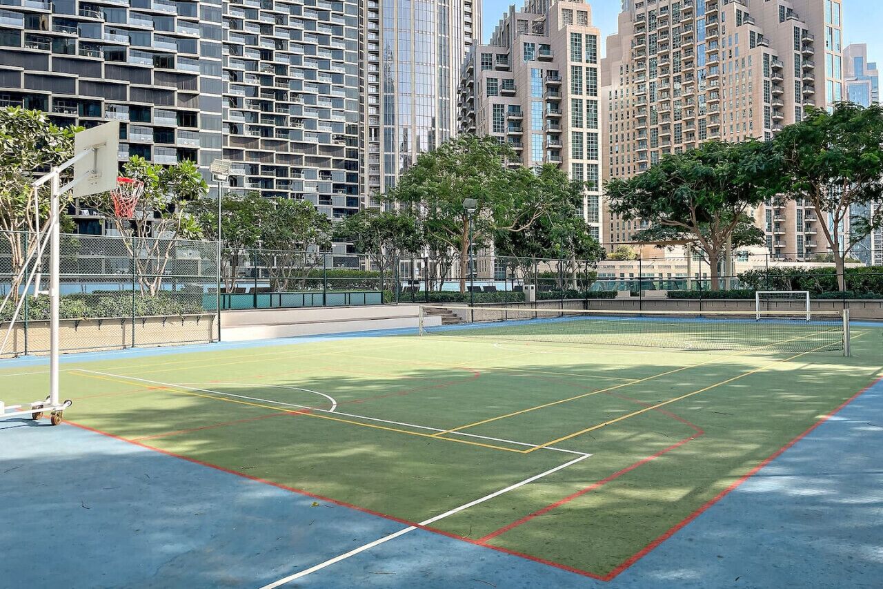 An outdoor tennis court surrounded by high-rise buildings.