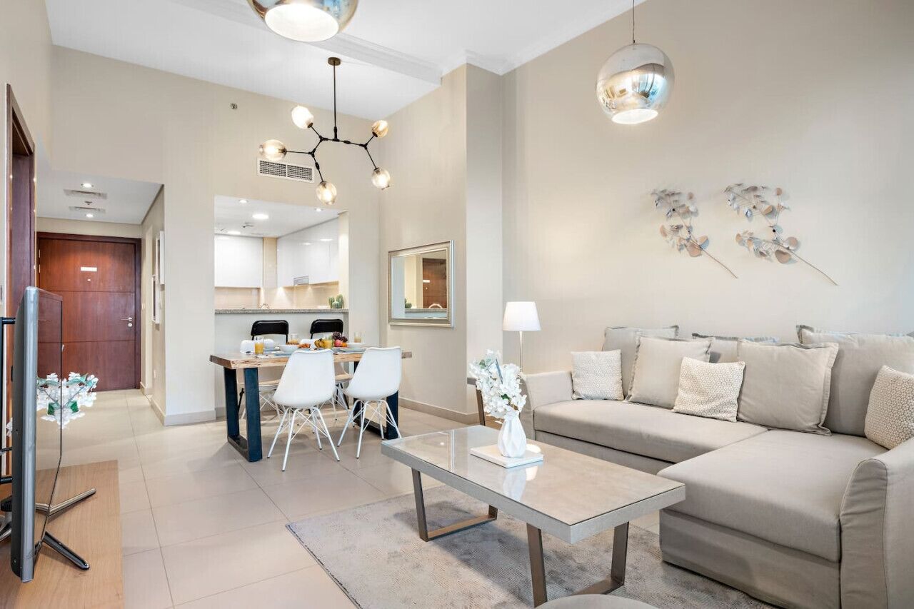 A modern living room with a sofa, a coffee table, and a dining area with chairs and a table.