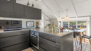 A modern kitchen with dark cabinetry, a large island, and pendant lighting.